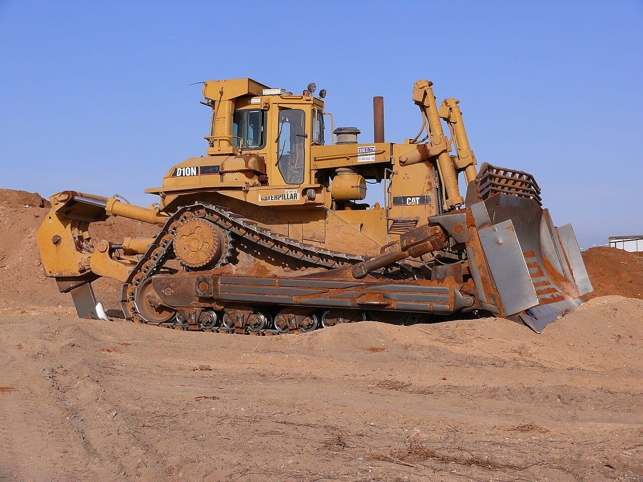 Large crawler bulldozer with ripper on a sand mound