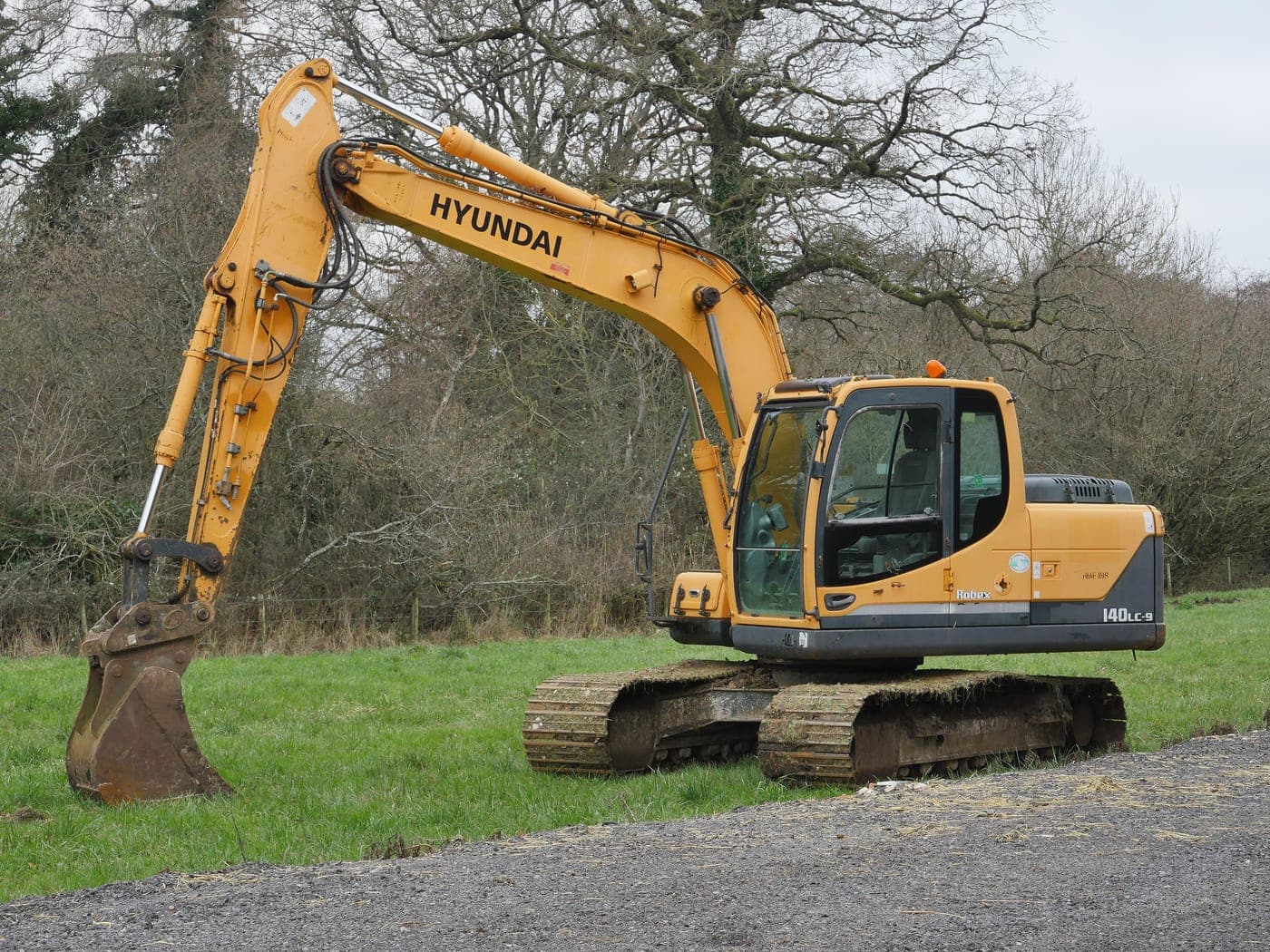 Crawler excavator with bucket lowered on a grass verge