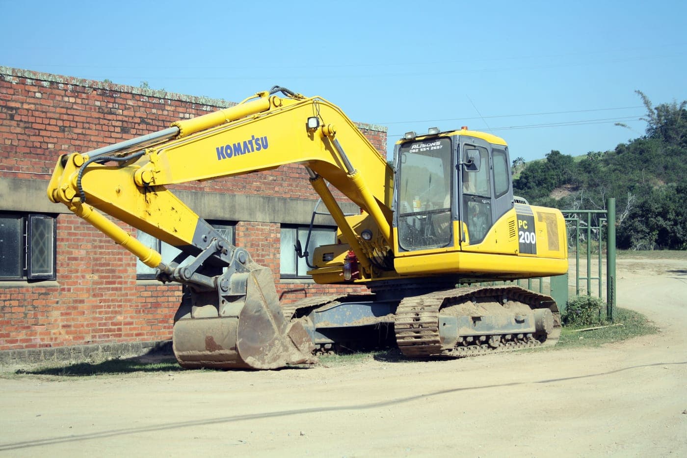 Mid-size crawler excavator parked beside a brick building
