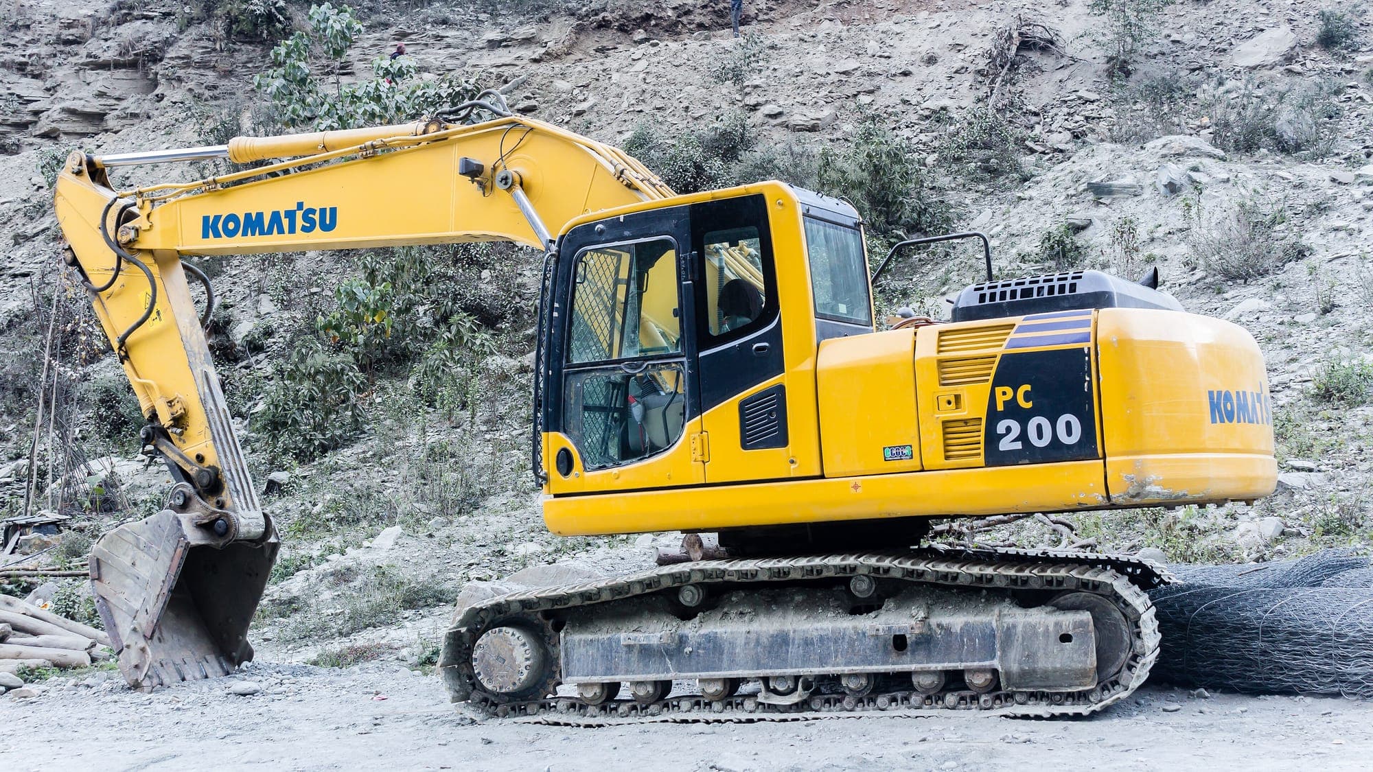 Yellow crawler excavator working on a rocky mountain site